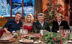 Andreas Erber, Beatrice Egli, Andy Borg und Hansi Hinterseer sitzen an einem weihnachtlich gedeckten Tisch.