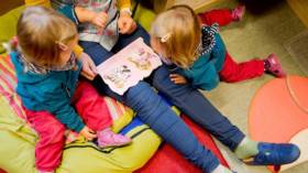 Eine Erzieherin liest mit Zwillingen ein Buch in einer Kindertagesstätte der Arbeiterwohlfahrt (AWO). © Julian Stratenschulte/dpa