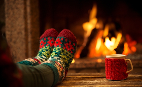 hochgelegte Füße mit Weihnachtssocken, gemütlich vor einem Kamin