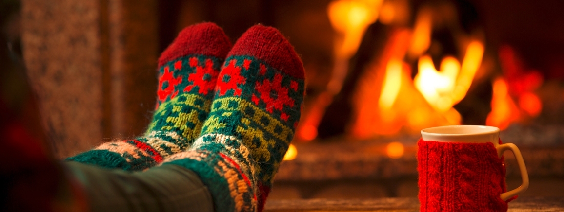 hochgelegte Füße mit Weihnachtssocken, gemütlich vor einem Kamin