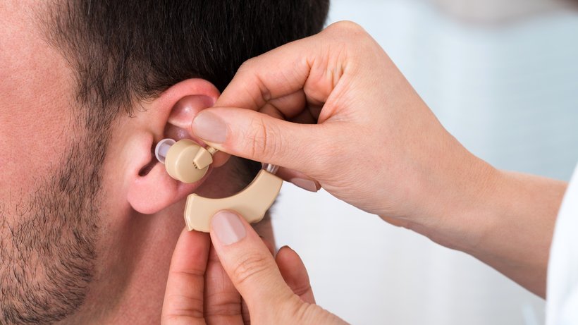 Eine Ärztin legt einem Patienten ein Hörgerät an. Je früher Hörgeräte zum Einsatz kommen, desto besser bleibt das Gehör erhalten. Auch bei einem irreversiblen Hörsturz. © Andrey Popov/shutterstock.com
