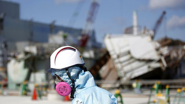  Ein Arbeiter im Februar 2016 auf der Anlage des havarierten AKW Fukushima-Daiichi: Im Hintergrund ist der Reaktorblock 1 zu erkennen. Seine Hülle flog vor fünf Jahren als erstes in die Luft. © Toru Hanai/AFP/Getty Images 