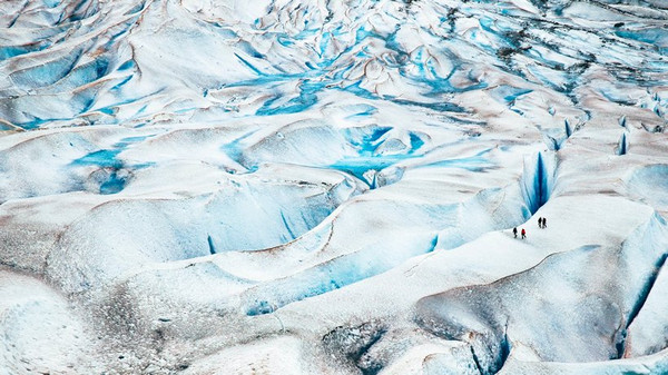 Vier ameisengroße Gestalten spazieren durch die Gletscherlandschaft. © unsplash.com/@kysondana